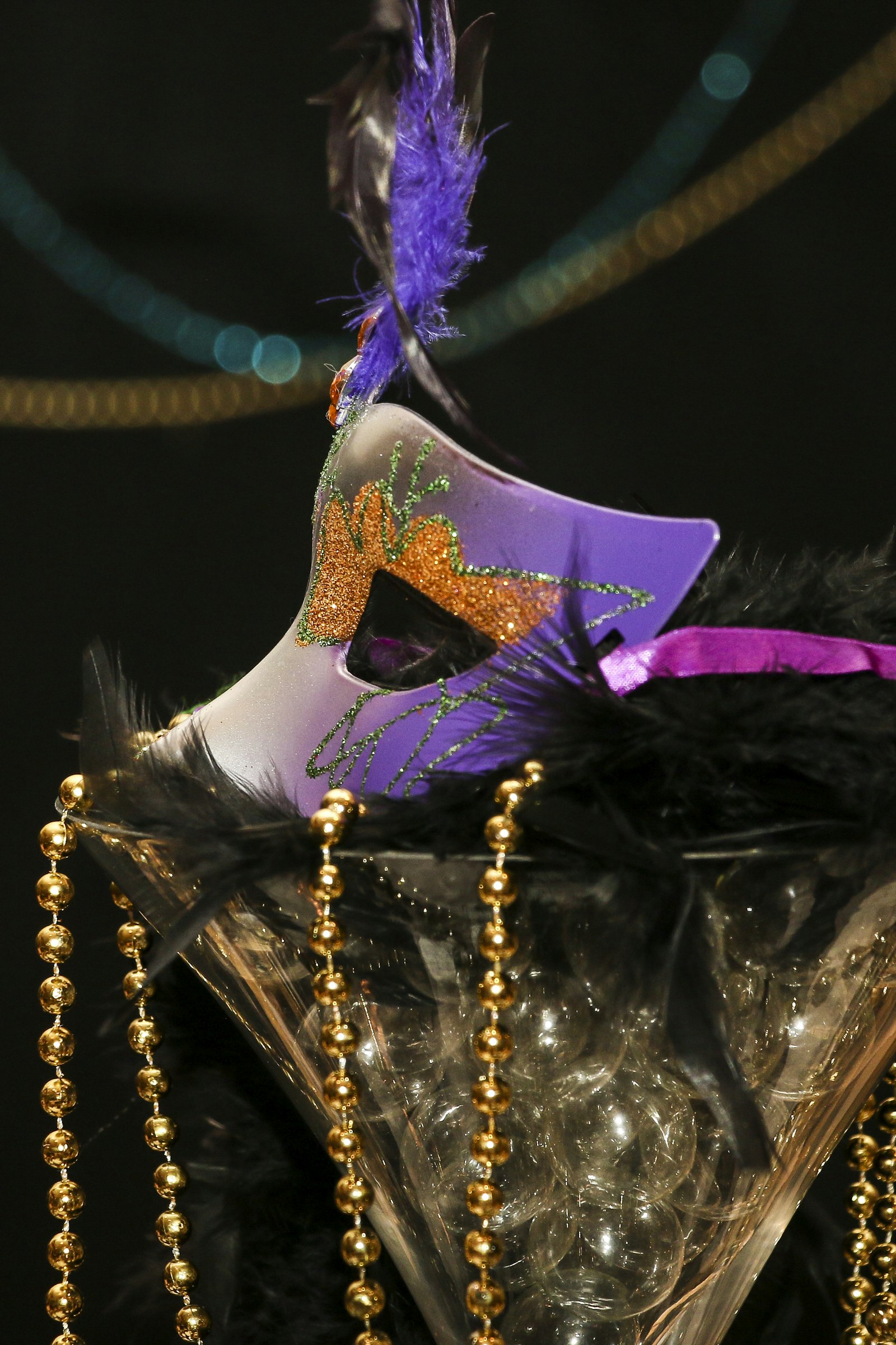 Purple Mardi Gras mask with feathers and gold bead necklaces in the classic Carnival colors