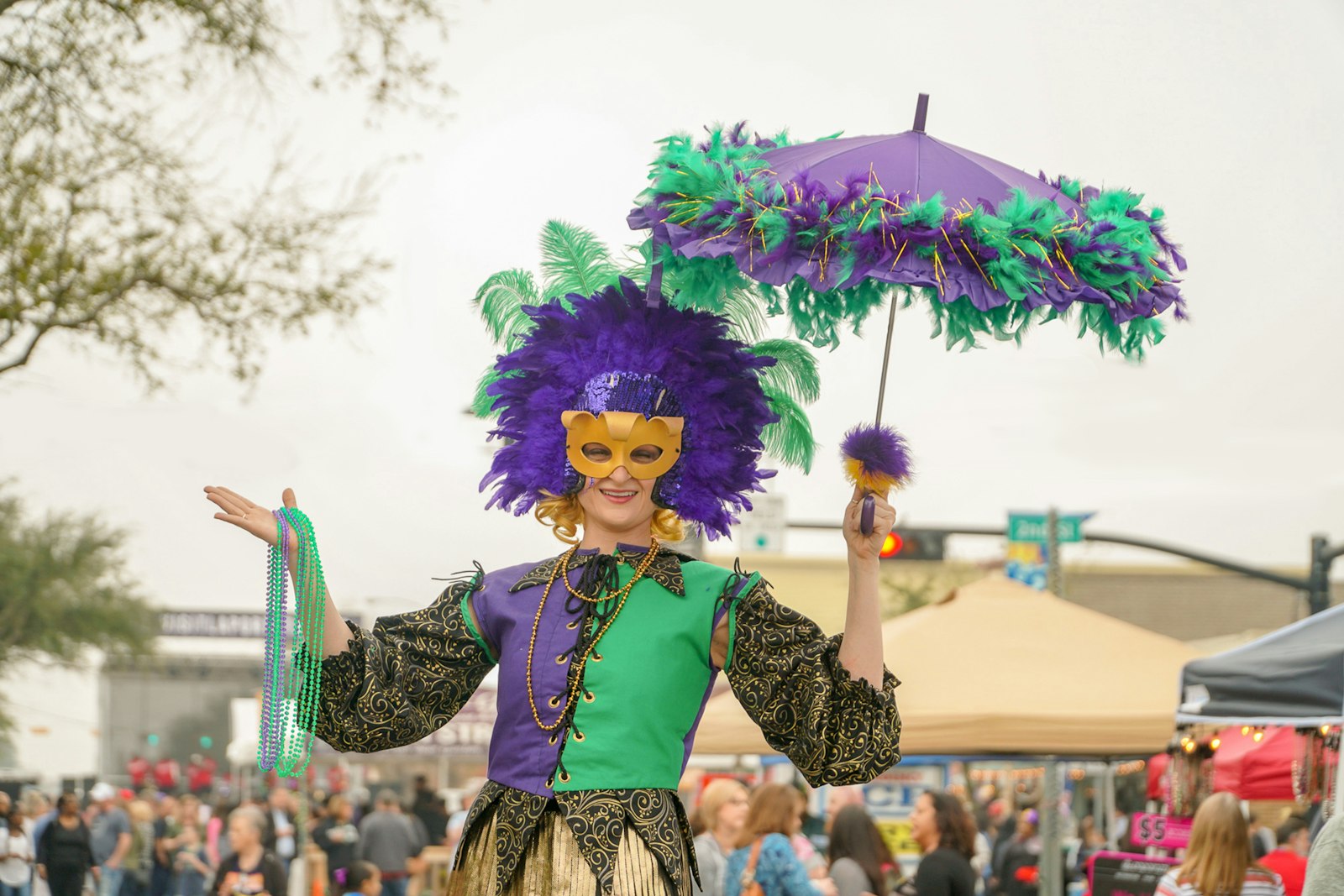 Costumed reveler in a purple and white outfit holding a decorated second-line umbrella