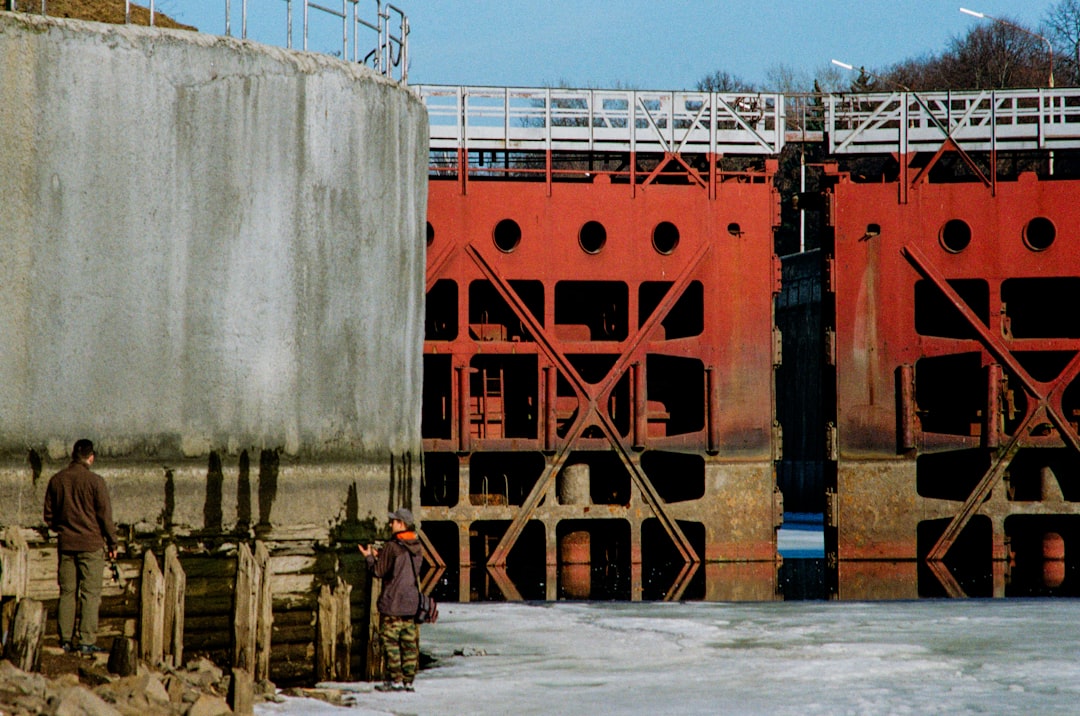 Two people stand by a large industrial lock gate