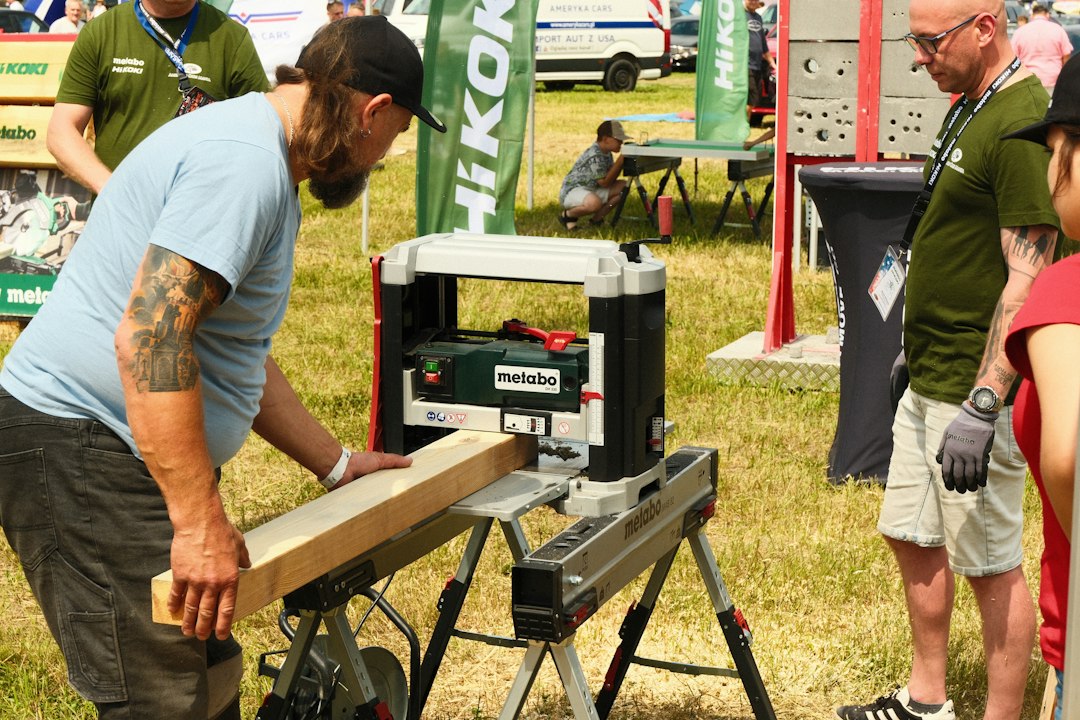 Man operating a woodworking planer with a wooden plank