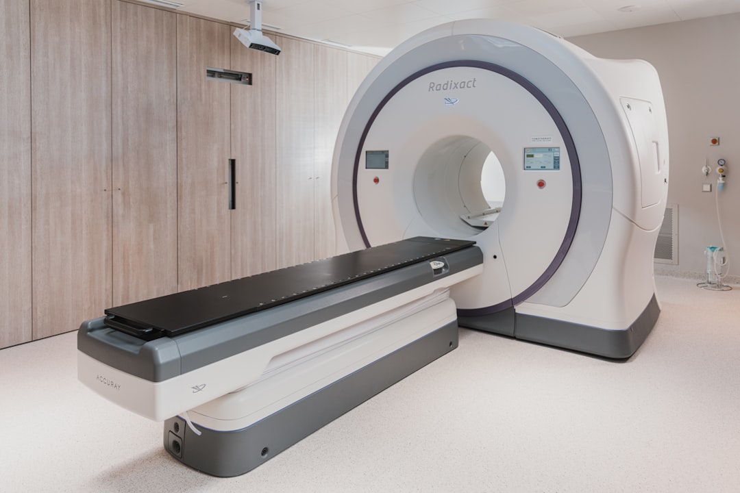 A white medical radiation therapy machine with a black patient table in a clinic