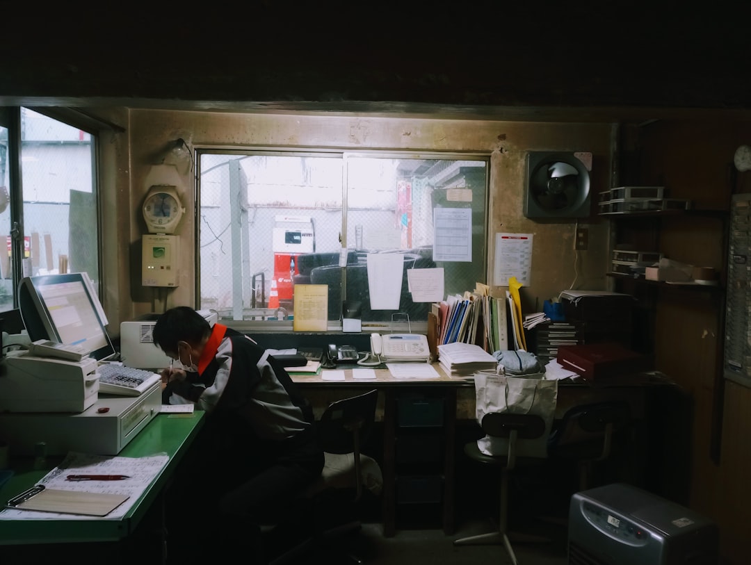Man working at a cluttered desk with a computer.