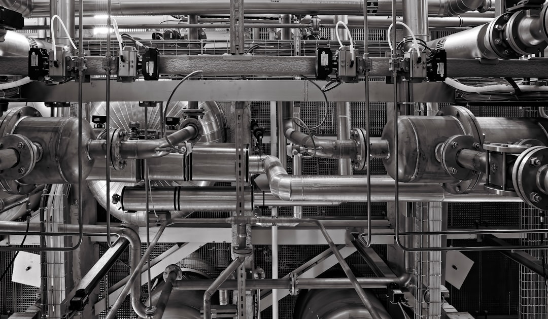 A complex network of industrial metal pipes and valves in a factory setting