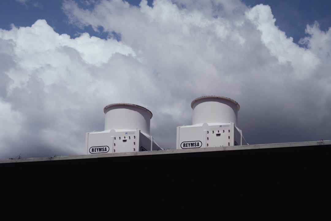 Two white devices on a rooftop against a cloudy sky.