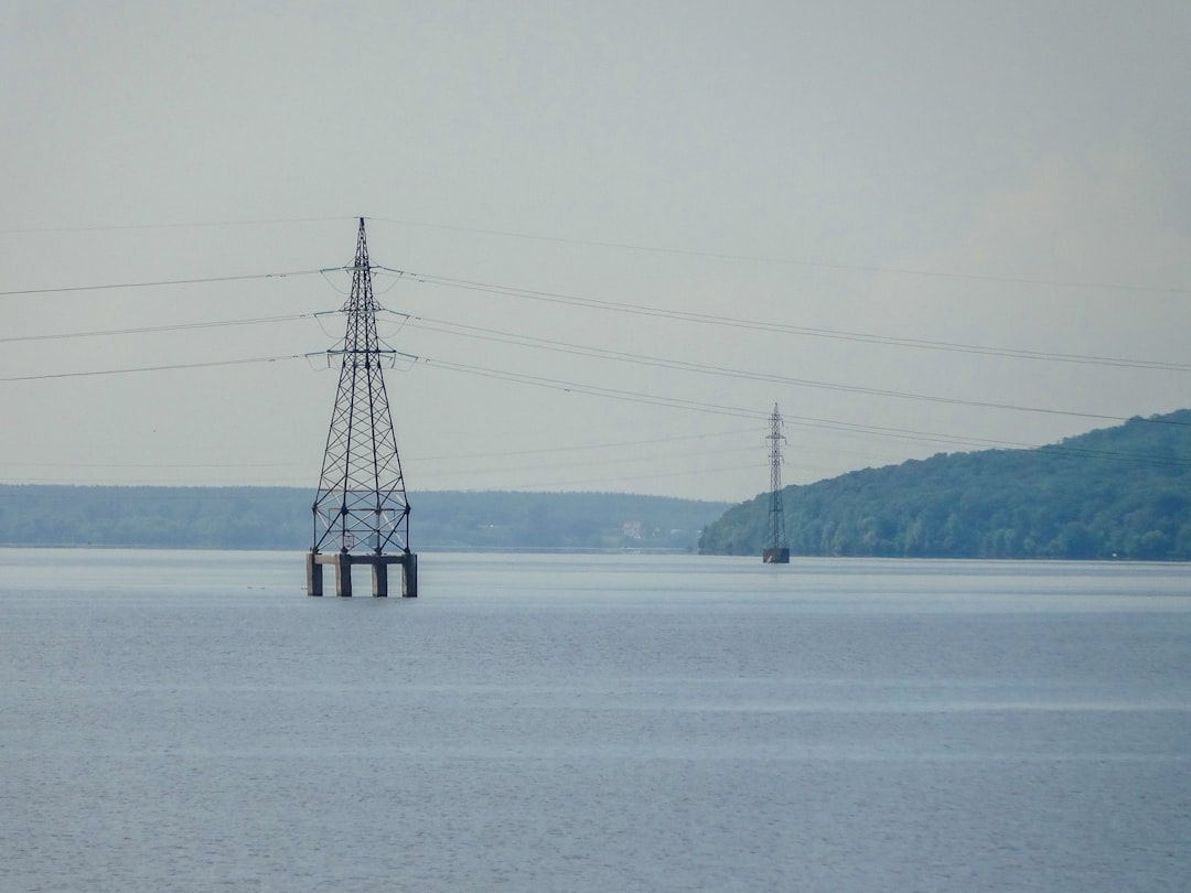 Power towers stand in a calm body of water.