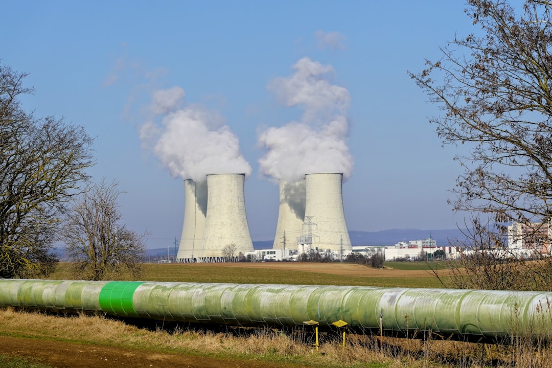 Cooling towers emitting steam against a clear sky.