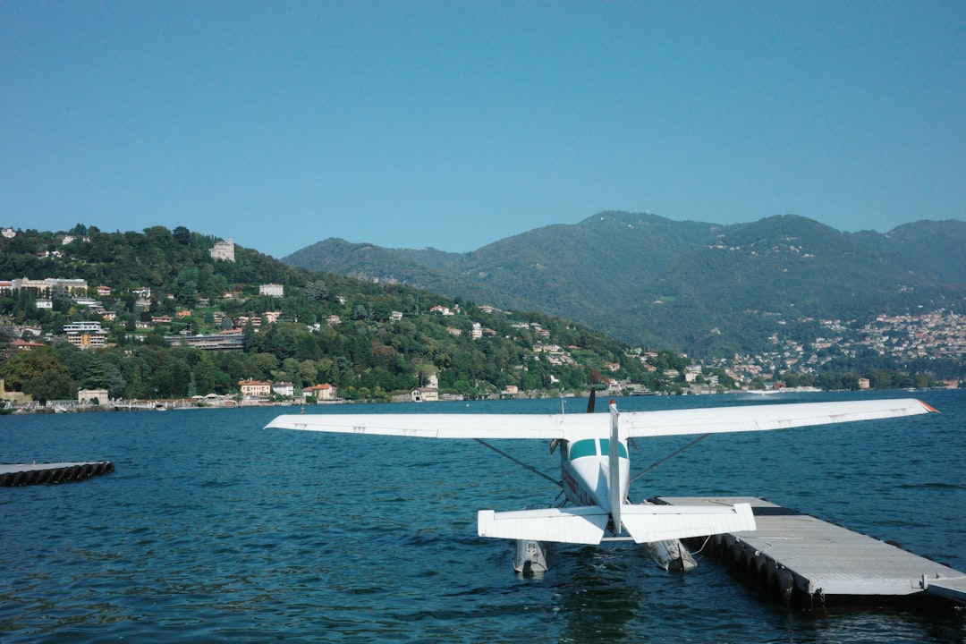 Seaplane docked on a calm lake with hills beyond.