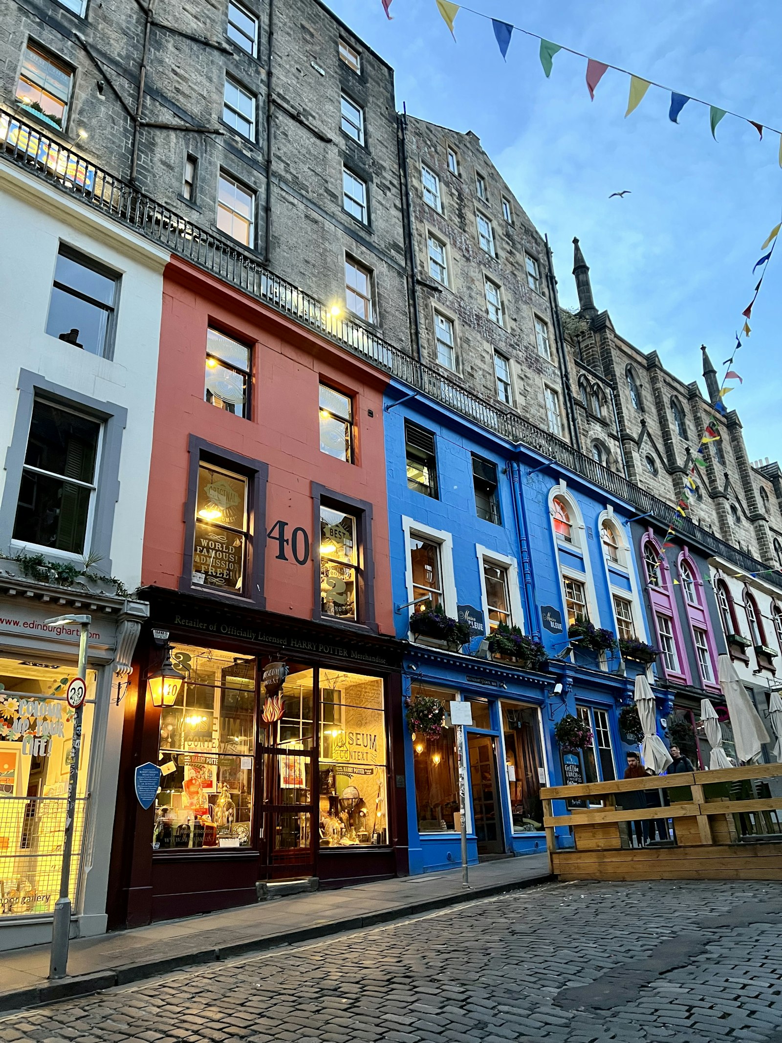Colourful shopfronts and restaurants along the cobblestones of Victoria Street in Edinburgh's Old Town. Photo by Scotland on Unsplash (unsplash.com/@scotland).